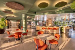 a restaurant with orange chairs and tables in a lobby at Spa Jardines de Lorca in Lorca