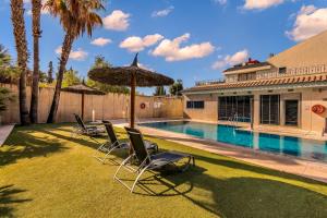a yard with chairs and an umbrella and a swimming pool at Spa Jardines de Lorca in Lorca