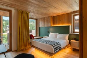 a bedroom with a bed and a large window at HOTEL de LEN in Cortina dʼAmpezzo