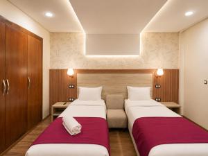 two beds in a hotel room with red sheets at Dakhla Sur Mer Hôtel in Dakhla