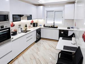 a white kitchen with white appliances and a table and chairs at Tetouan house vue- chambre climatisée in Tétouan