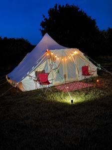 a tent with chairs in a field at night at West Holme Glamping in Wareham