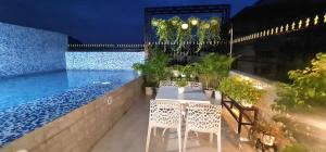 a table and chairs next to a swimming pool at night at Vedic village Rai villa in Sikarpur