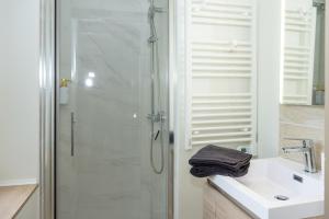 a white bathroom with a shower and a sink at La Suite Cacao in Saint-Rambert-dʼAlbon