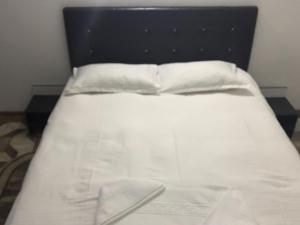 1 cama con cabecero negro y 2 almohadas blancas en Pensiunea Marcello, en Iaşi