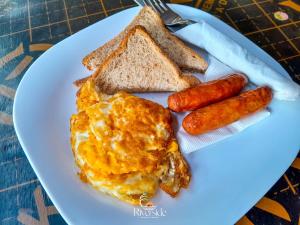 a plate of breakfast food with eggs sausage and toast at Riverside chania resort in Nyeri