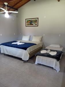 a bedroom with two beds and a ceiling fan at Chalé caminho das cachoeiras in São Thomé das Letras