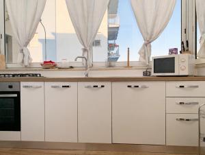 a kitchen with white cabinets and a microwave and a window at Casa Vacanze Formia in Formia