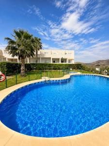 a large blue swimming pool in front of a house at Los cántaros Apartamento Mojácar in Mojácar