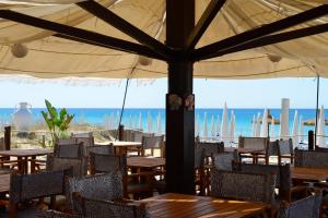 ein Restaurant mit Tischen und Stühlen und dem Meer in der Unterkunft Tuareg Hotel in Campomarino