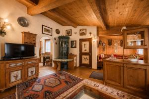 a large living room with a television and wooden ceilings at Cesa Linda by AMA Val di Fassa in Campitello di Fassa