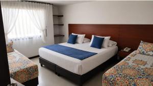 a bedroom with a large bed with blue pillows at Hotel Casa Lamay in Bogotá +8 photos
