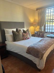 a bedroom with a large bed with pillows at Rose Cottage De Hoop Farm PAARL SOUTH in Hartebeeskraal