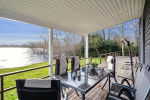 a porch with a table and chairs and a view of the water at Luxury Lakeside Retreat in Ringsted