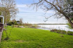 a grassy yard with a lake in the background at Luxury Lakeside Retreat in Ringsted