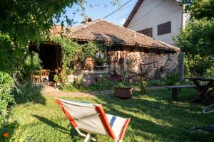 a chair sitting in the grass in front of a house at Etno Kuca Bajka in Mataruška Banja