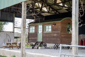 a small wooden cabin with a table and a bench at Northcombe Farm Shepherd's Hut in Germansweek +6 photos