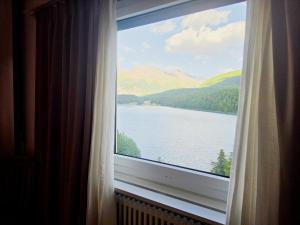 a window with a view of a lake and mountains at Splendida dimora vista lago in St. Moritz