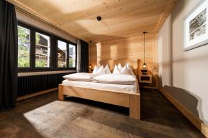 a bedroom with a bed in a room with windows at Hotel Arc-en-ciel Gstaad in Gstaad +75 photos