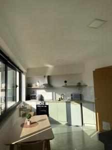 a kitchen with white cabinets and a table in it at Lindo Verde T1 in Ventosa