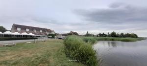a body of water next to a house and a lake at Logis Hôtel Auberge de la Gabrière in Lingé
