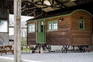 a dog sitting in front of a tiny house at Northcombe Farm Shepherd's Hut in Germansweek