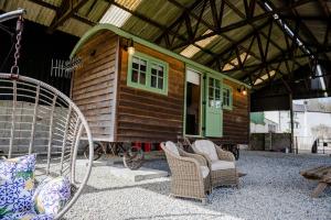 a tiny house with chairs and a porch at Northcombe Farm Shepherd's Hut in Germansweek