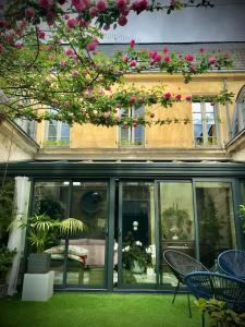a building with windows and chairs and pink flowers at La maison de Yan in Cognac