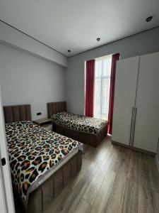 a bedroom with two beds in a room with wooden floors at Alfa white resort in Koshkolʼ