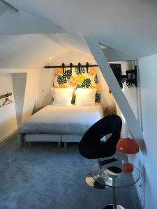 a bedroom with a white bed and a black chair at La maison de Yan in Cognac