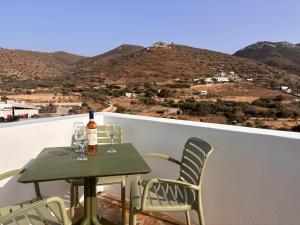 a green table and chairs on a balcony with mountains at Apollonia Studios in Katapola