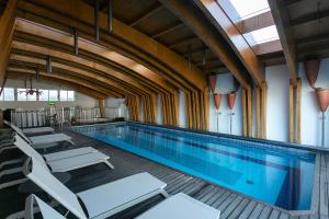 a large swimming pool with white lounge chairs in a building at Hotel Ponta Delgada in Ponta Delgada