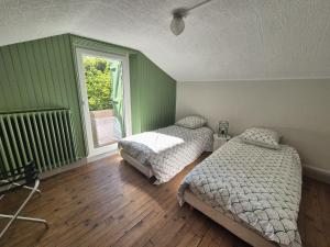 two beds in a room with green walls and wooden floors at L'Ostal De Papi in Saint-Affrique