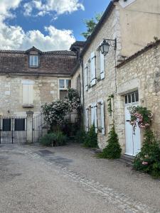an old stone house with white doors and a gate at La Maison Colette - B&B in Issigeac