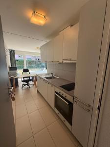 a kitchen with white cabinets and a table with a chair at Apart Leman in Ecublens