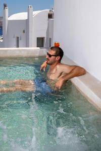 a man sitting in a swimming pool at Arvanitis Cave Village in Akrotiri