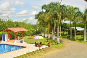 a resort with a pool and a gazebo and palm trees at Finca Hotel Loma del Café in Pueblorrico