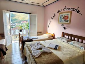 two beds in a room with a sign on the wall at Pousada das Hortensias in Conservatória +56 photos