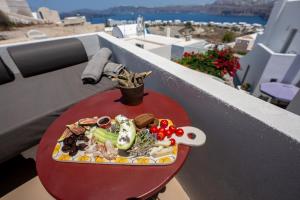 a plate of food on a red table on a balcony at Arvanitis Cave Village in Akrotiri