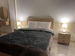 a bedroom with a large bed and two lamps on tables at Neat & Modern Studio 2Mins Pyramids - Royal desert Inn in Cairo