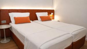 two beds in a small room with orange pillows at NFK The House Hotel in Antalya