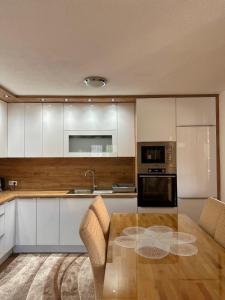 a kitchen with a wooden table and white cabinets at Hajr Villa in Ilidža
