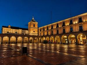 a large building with a clock tower at night at Apartamento Premium Ávila PLAZA MAYOR con PARKING in Ávila +24 photos
