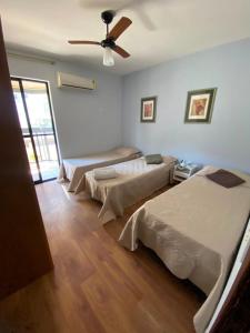a room with three beds and a ceiling fan at Apto MAR AZUL CARIBE - PRAIA DO FORTE - 3 minutos a pé da praia in Cabo Frio