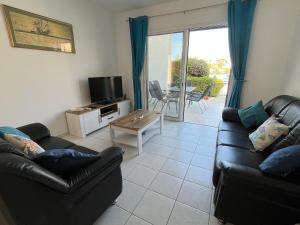 a living room with two leather couches and a television at Pegeia Sun in Peyia