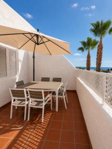 a table and chairs on a balcony with an umbrella at Los cántaros Apartamento Mojácar in Mojácar