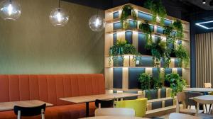 a restaurant with tables and plants on the wall at B&B HOTEL Kielce Centrum in Kielce