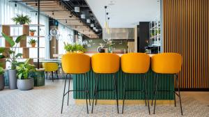 a group of yellow chairs in a room with plants at B&B HOTEL Kielce Centrum in Kielce