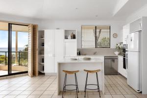 a kitchen with white cabinets and a counter with stools at Penthouse with Incredible Views & Pool in Noosa Heads
