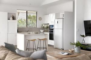 a white kitchen with a couch and a kitchen with a counter at Penthouse with Incredible Views & Pool in Noosa Heads +14 photos